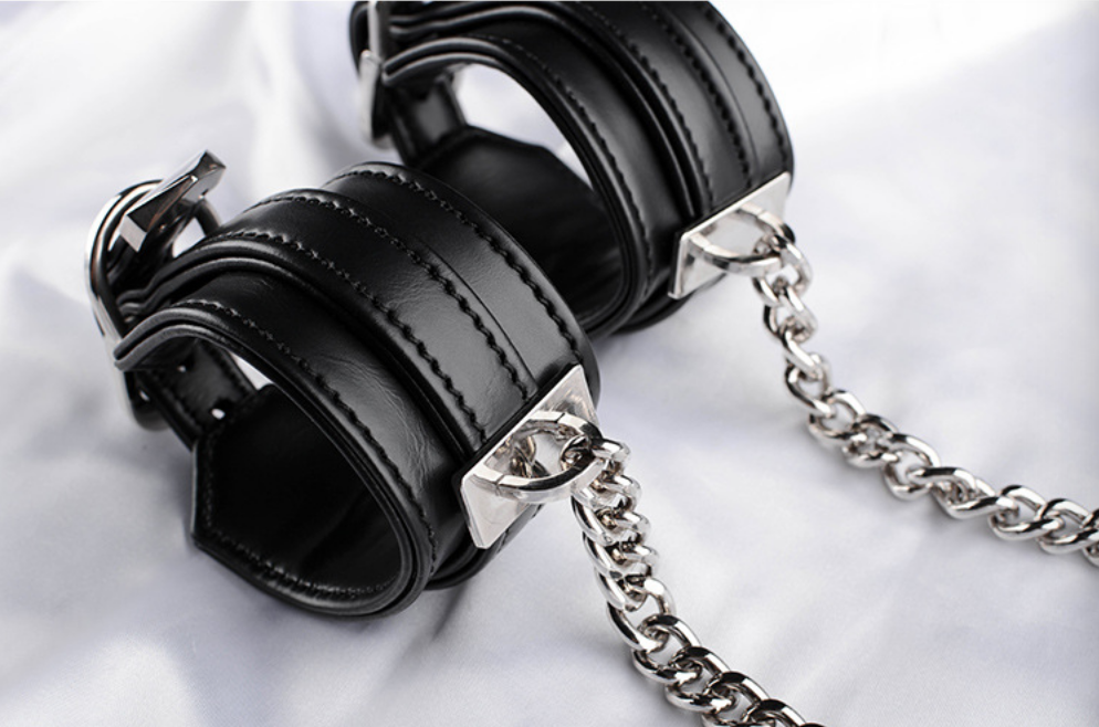 A pair of Black Sex Handcuffs with heart lock and chain